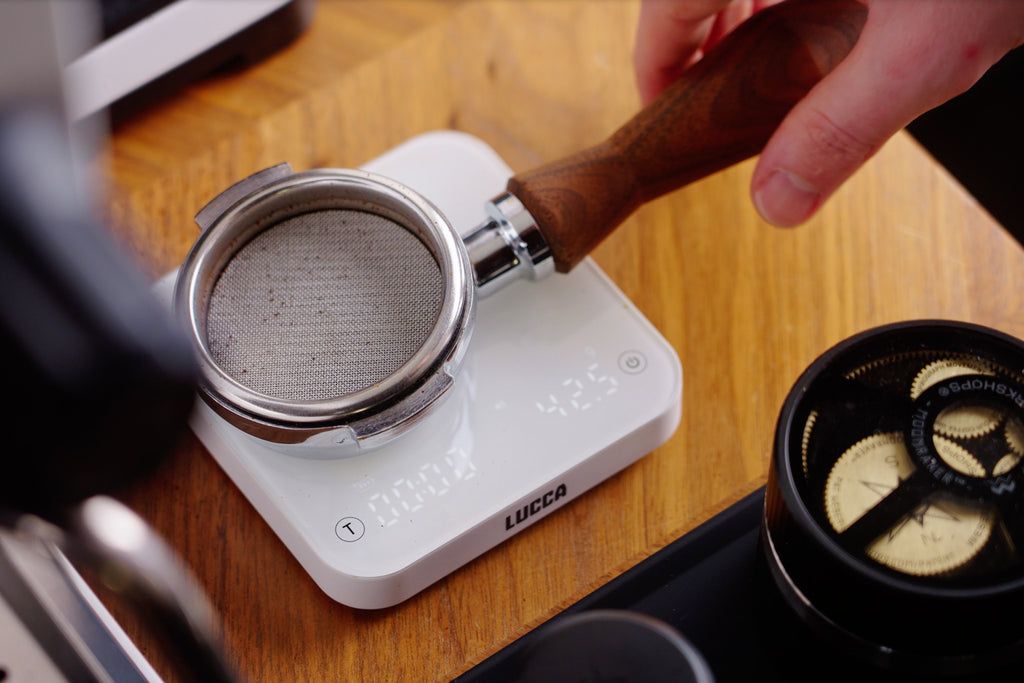 Portafilter with a puck screen on top of a scale lifestyle by Clive Coffee